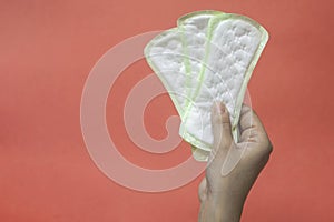 Woman`s hands holding feminine hygiene pads. Hands of female hold menstrual pads or sanitary napkins for women photo