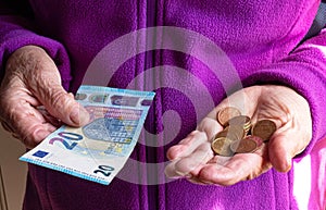 Woman`s hands are holding a few euro coins. Pension, poverty, social problems and the theme of old age. Saving.