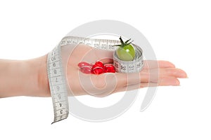 Woman's hands holding green tomato, pills