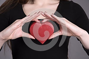 Woman`s hands holding a heart shape box