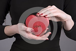 Woman`s hands holding a heart shape box with the word Love imprinted