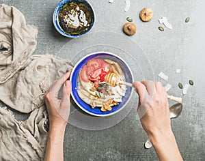 Woman`s hands holding honey drizzlier and blue healthy breakfast bowl