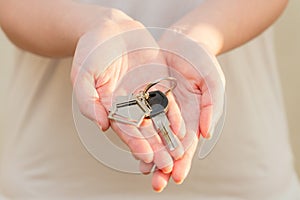 Woman's hands holding key with keychain in shape of the house