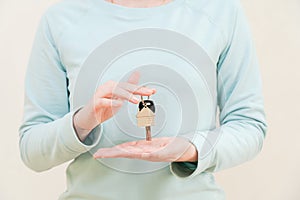 Woman's hands holding key with keychain in shape of the house