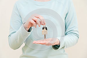 Woman's hands holding key with keychain in shape of the house