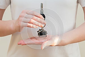 Woman's hands holding key with keychain in shape of the house