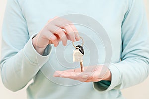 Woman's hands holding key with keychain in shape of the house