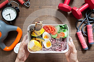 Woman`s hands holding lunch box with rice berry, boiled eggs, sw