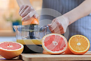 Woman`s hands is holding a orange half and making juice