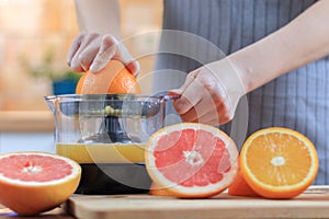 Woman`s hands is holding a orange half and making juice