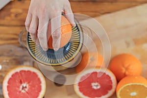 Woman`s hands is holding a orange half and making juice