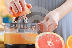 Woman`s hands is holding a orange half and making juice