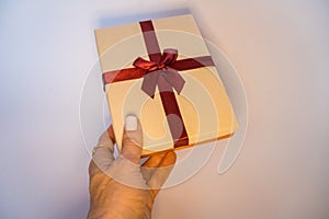 Woman& x27;s hands are holding present box with dark red bow on a isolated background