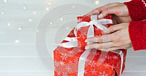 Woman`s hands are holding a red gift box for Christmas or New Year . Buying gifts for the New Year and Christmas holidays. Ð¡lose