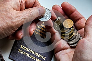 Woman`s hands holding russian coins over the pension certificate.