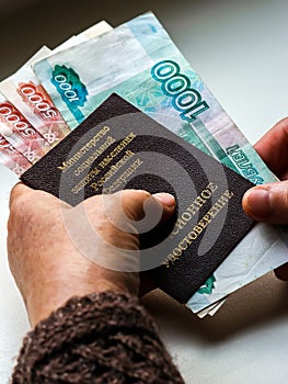 Woman`s hands holding russian pension certificate and russian rubles.