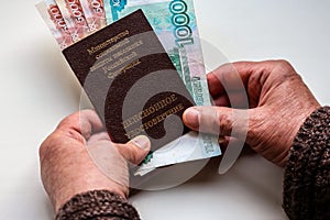 Woman`s hands holding russian pension certificate and russian rubles.