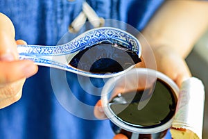 Woman`s Hands Holding Spoon with Black Chinese Herb Jelly Named Guiling Gao