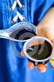 Woman`s Hands Holding Spoon with Black Chinese Herb Jelly Named Guiling Gao