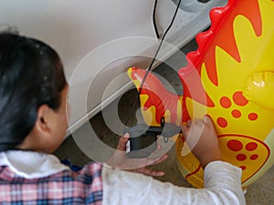 Woman`s hands holding and using mini air pump, connected to the car plug, to inflate a rocking doll