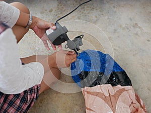 Woman`s hands holding and using mini air pump, connected to the car plug, to inflate a rocking doll