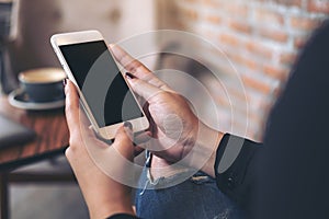 Woman`s hands holding and using white mobile phone with blank black desktop screen