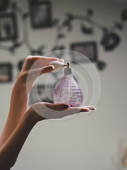 Woman's hands holding a vintage perfume glass bottle