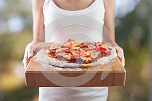 Woman's hands holds homemade pizza