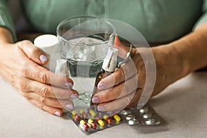 Woman& x27;s hands holds medicines - throat spray and ear spray bottles, blisters of capsules and pills and glass of