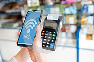 A woman`s hands holds a payment terminal with a check and pays for a purchase using a smartphone.On the phone screen-wi-fi networ