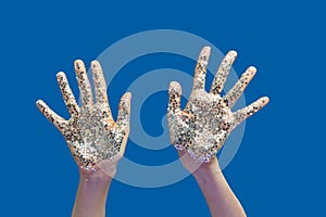 Woman`s hands with holiday decoration glitter small stars on a blue.