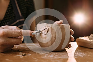 Woman& x27;s hands with homemade handmade clay or ceramic pot. The clay master sculpts the product in the kitchen. Home
