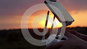 Woman`s hands keep a control panel to operate a drone at sunset