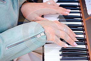 Woman's hands on the keyboard of the piano.Piano learning chords at home.woman playing digital keyboard with online music
