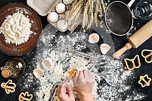 Woman`s hands knead dough on table with flour, eggs and ingredients. Top view.