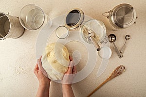 Woman`s hands kneading dough on kitchen table, top view