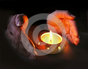 Woman's hands lit by a Christmas candle