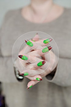 Woman\'s hands with long nails and green and brown thermo manicure