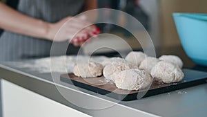 Woman`s hands making minced steak cutlets or meat balls of forcemeat. Pouring out cutlets in flour