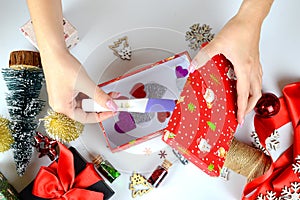 Woman's hands making a pregnancy test as a Christmas gift. table with decorations. View from above. Holiday mood, motherhood