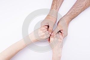 The woman`s hands in the man`s hands lie on a white background. Man and woman holding hands, relationship, marriage