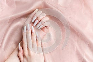 A woman\'s hands with a manicure on them, the nails are painted in a white color