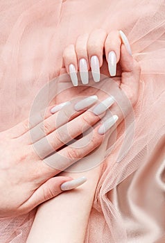 A woman's hands with a manicure on them, the nails are painted in a white color