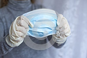 A woman`s hands in medical gloves hold a mask