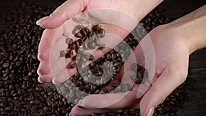 A woman`s hands is mix coffee beans.. Roasted coffee as background. Coffee grains as texture