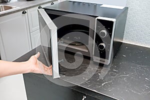 Woman`s Hands open microwave door