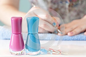 Woman's hands painting her nails with blue nail polish