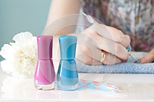 Woman's hands painting her nails with blue nail polish