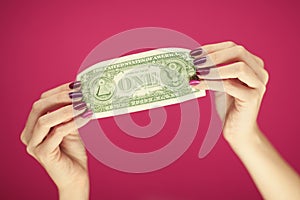 Woman`s hands with perfect, beautiful pink nail polish holding one dollar note