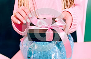 Woman`s hands with pink manicure holding black present box